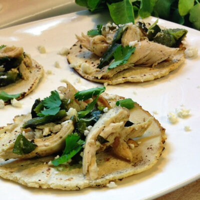 Poblano chicken tacos garnished with cilantro on a plate.