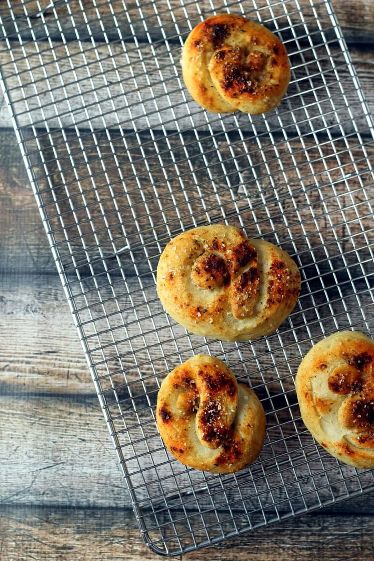 Baked Gourmet soft pretzels cooling on a wire rack with a golden crust and rustic shape.