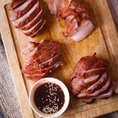 Sliced Char Siu Pork arranged on a wooden cutting board.