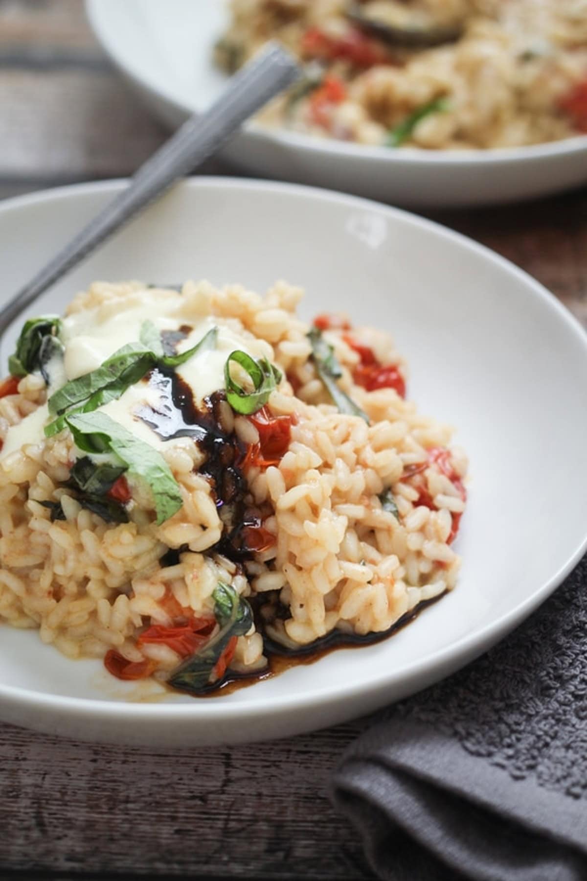 Tomato and basil risotto with mascarpone and balsamic glaze, served in a white bowl.
