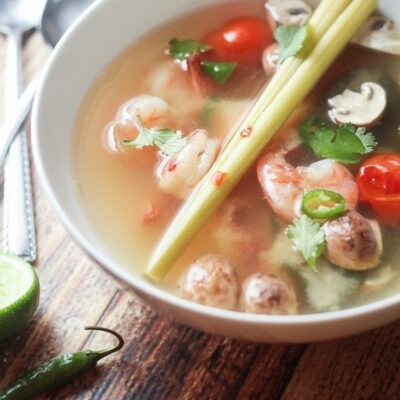 A bowl filled with Tom Yum Soup with shrimp.