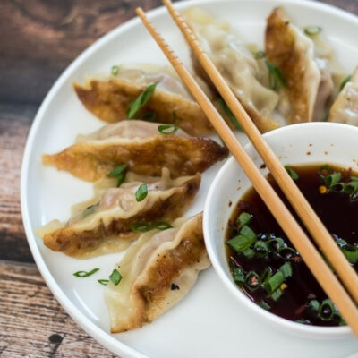 Chinese dumplings served on a plate with dipping sauce.