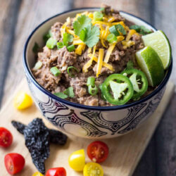 Bowl of vegetarian refried beans served with colorful vegetables.