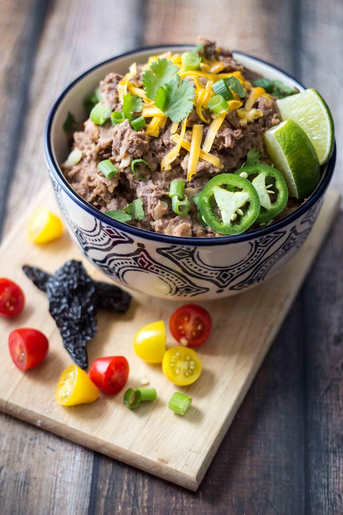 Bowl of refried beans served with colorful vegetables.