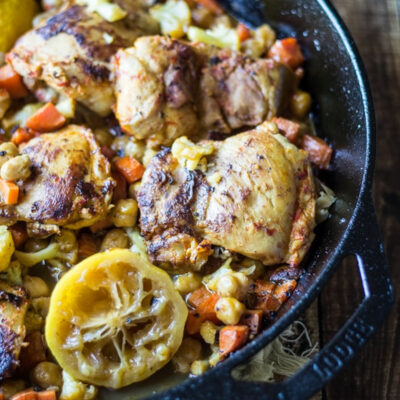 Harissa Chicken Thighs with caramelized lemon slices in a skillet.
