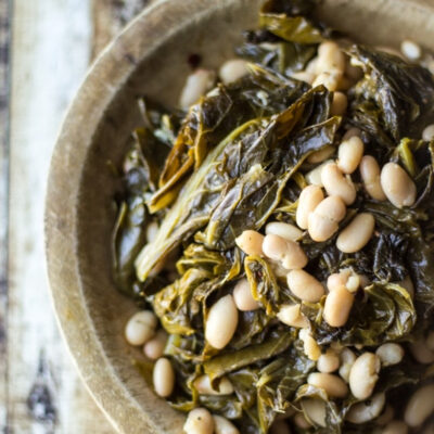 A rustic bowl filled with collard beans and greens.
