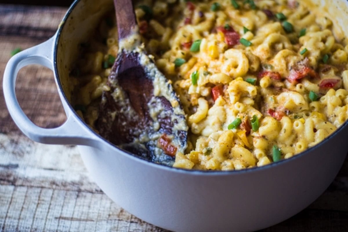 A partially stirred Cajun bacon macaroni and cheese in a white pot.