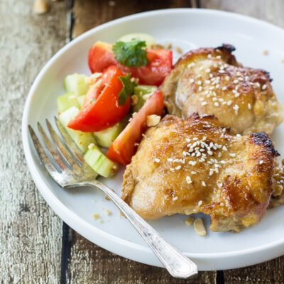Asian Sticky Chicken Thighs served with a fresh cucumber and tomato salad.