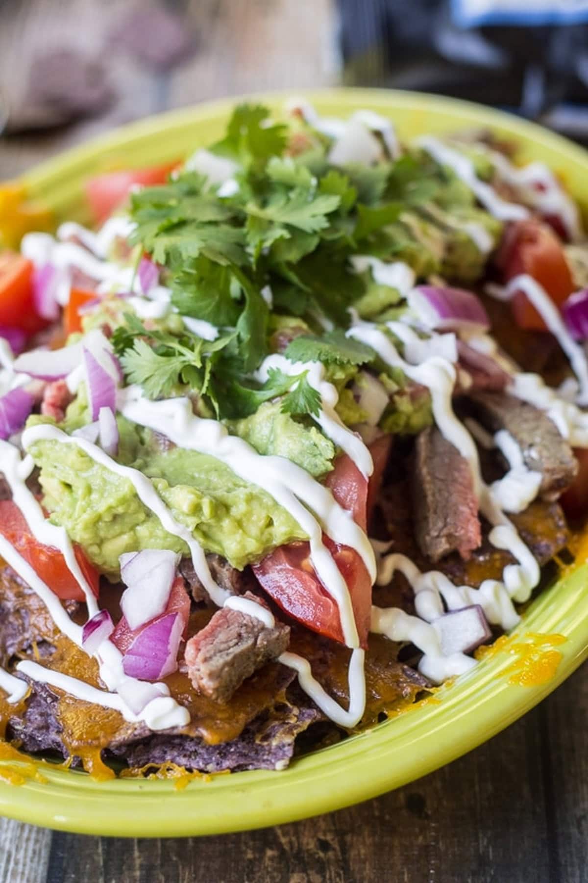 A plate of carne asada nachos with toppings.