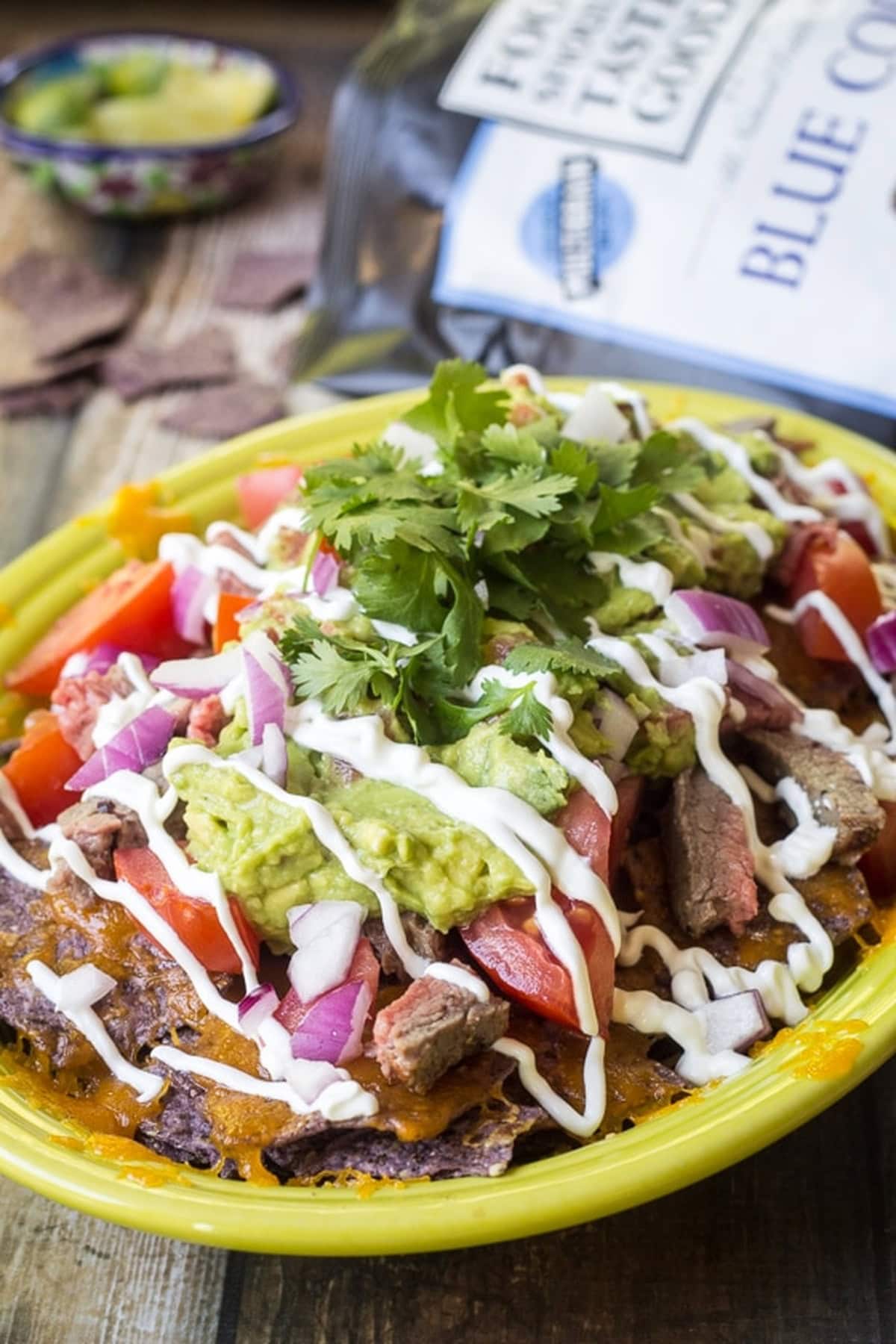 Carne asada nachos with melted cheese served on a yellow plate.