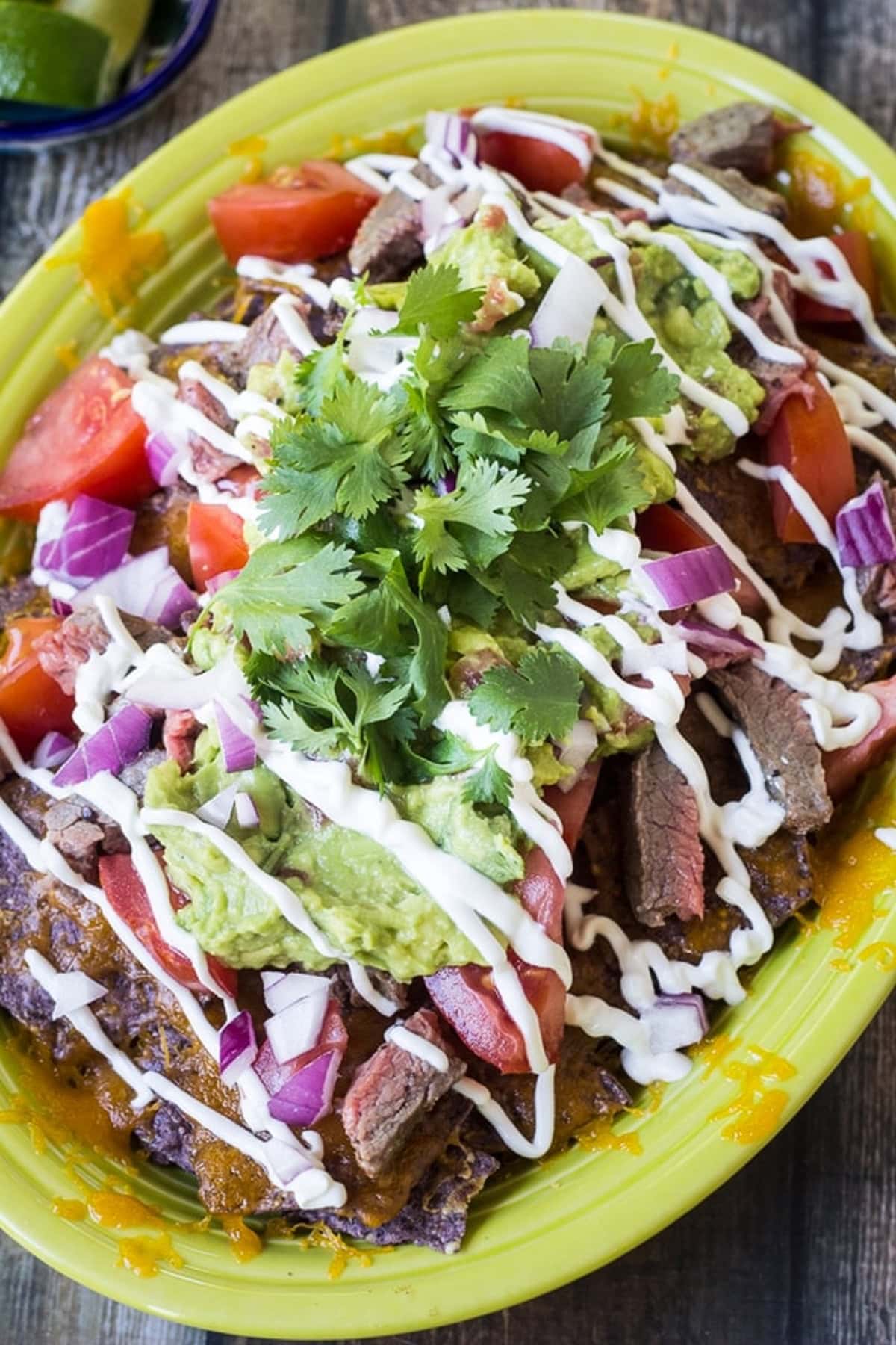 Top-down view of carne asada nachos with fresh toppings.