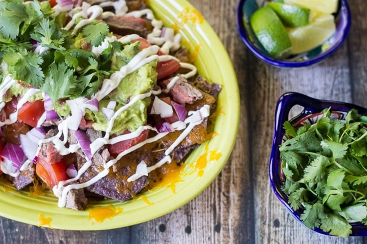 Grilled steak nachos ingredients arranged on multiple plates.