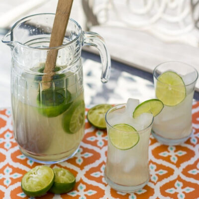 A pitcher and two glasses of Thai limeade on a table.