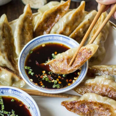 Vegan potstickers being dipped in sauce.