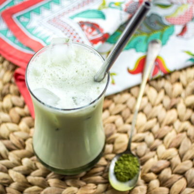 A glass of Iced Green Tea Latte served on a table.