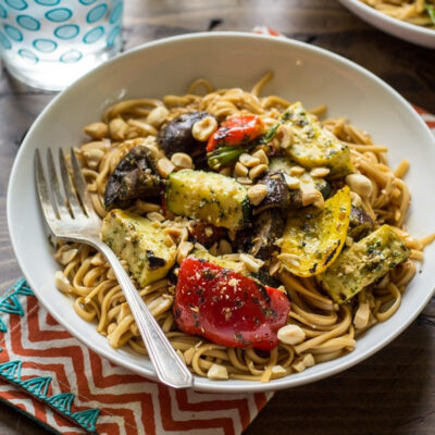 Veggie noodle bowls with chopped peanuts on top, served in a white bowl.