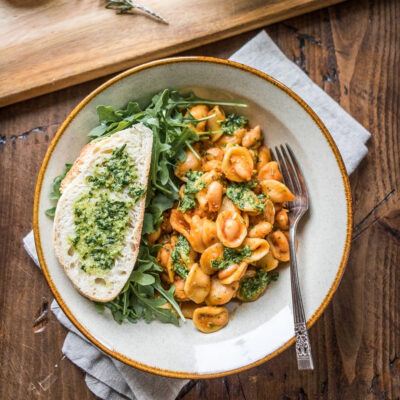 A plate with vegan pesto pasta served with bread.