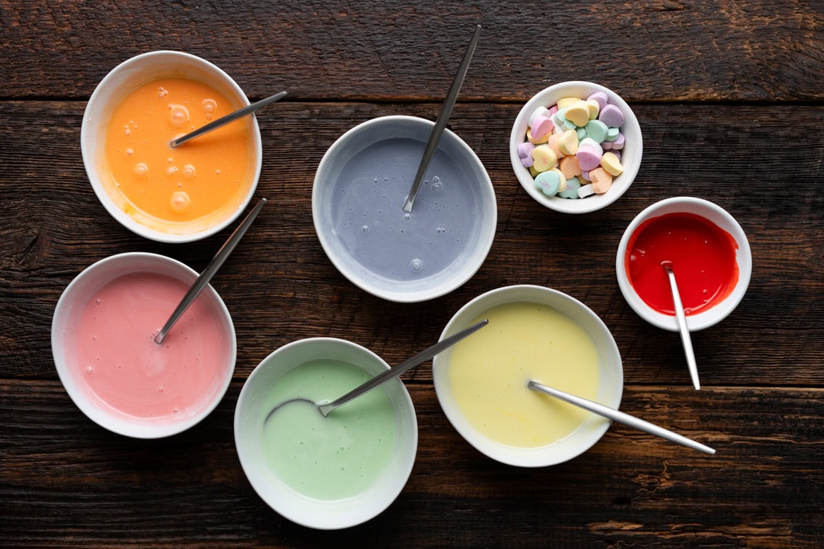 Royal icing separated into 6 bowls with individual colors.