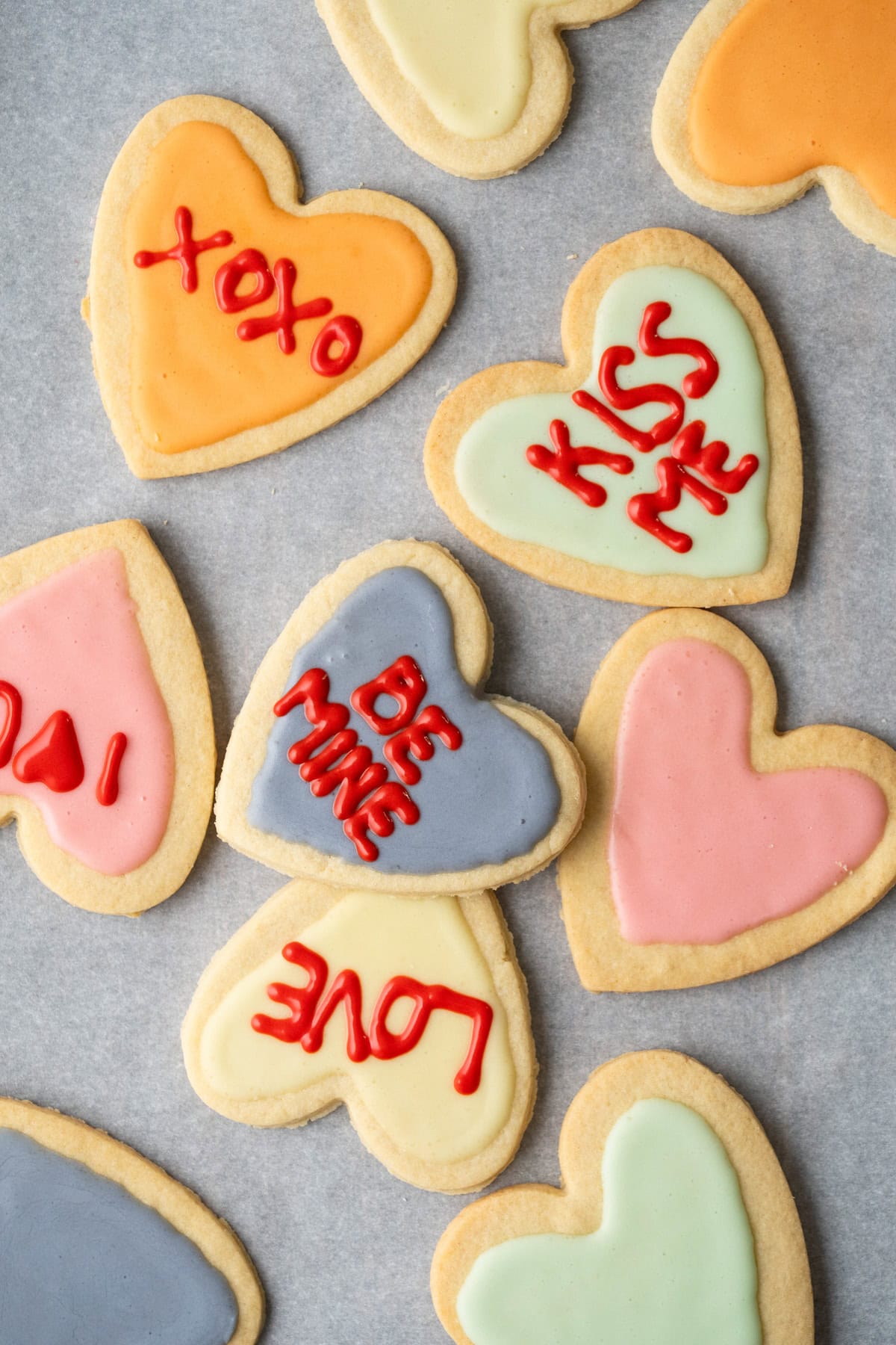 Decorated conversation heart cookies on parchment paper.
