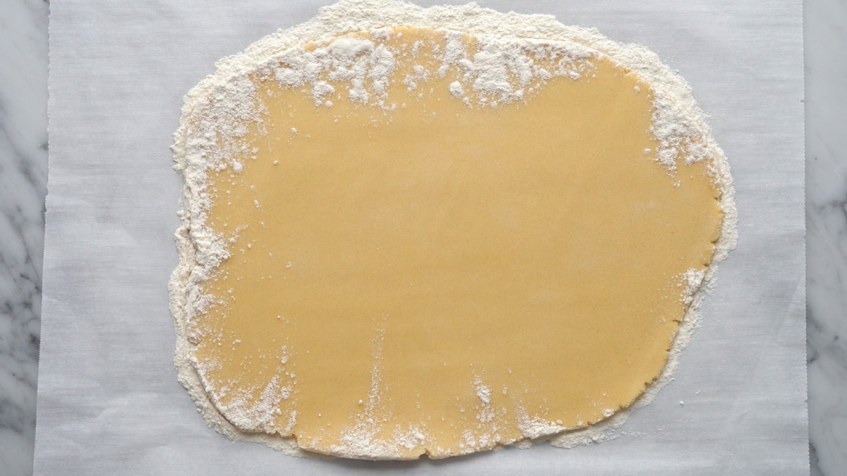 Cookie dough rolled out onto wax paper.