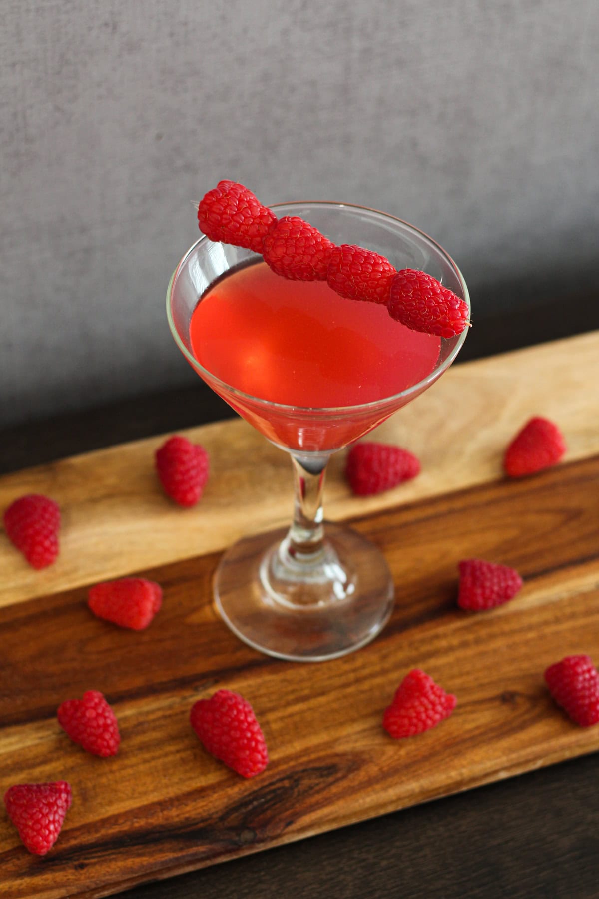 Raspberry martini on a wooden board with raspberries around.