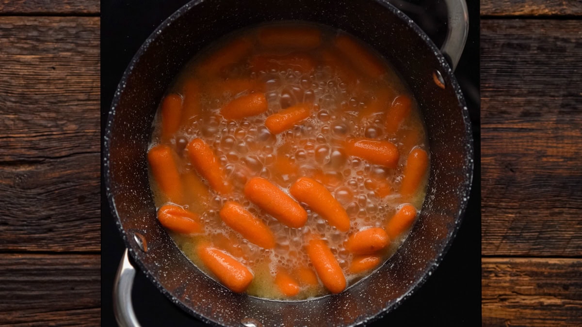 Brown sugar carrots boiling in a pot.