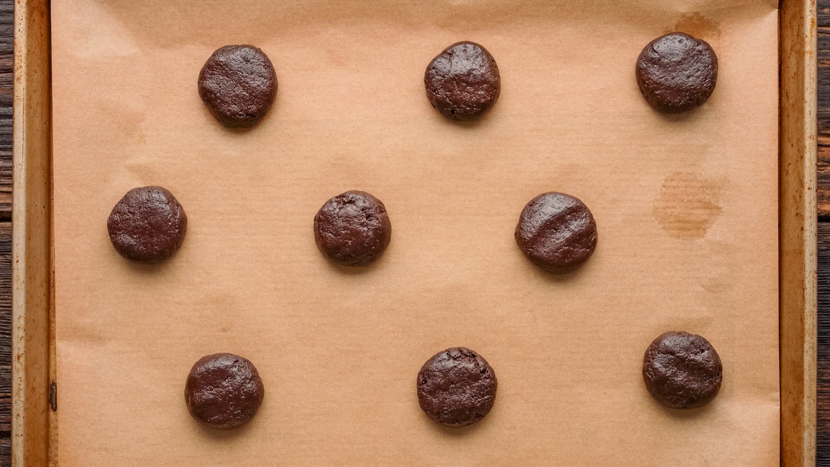 Cookie dough balls slightly flattened and placed on a cookie sheet.