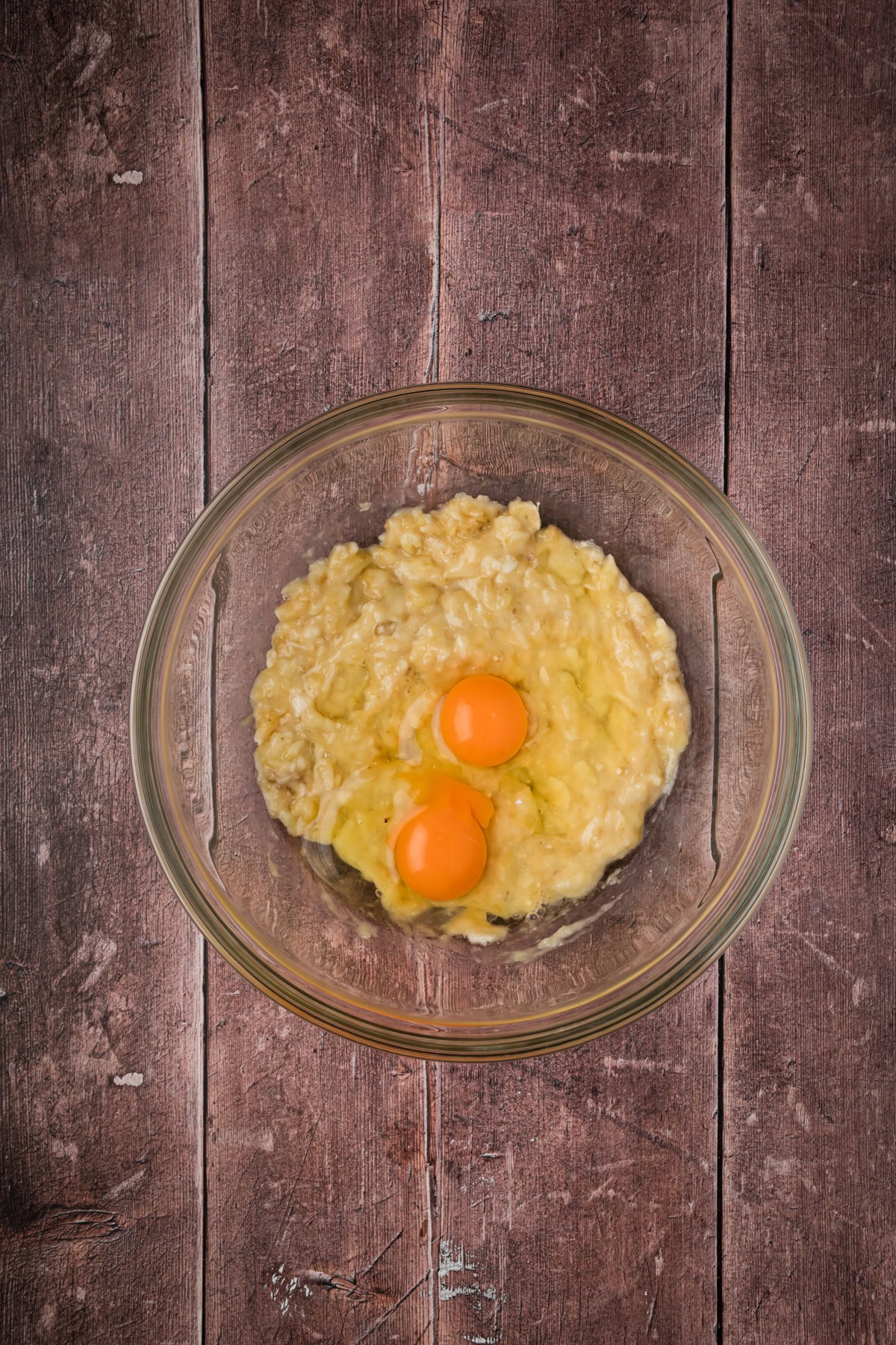 Mashed bananas and eggs in a glass bowl.
