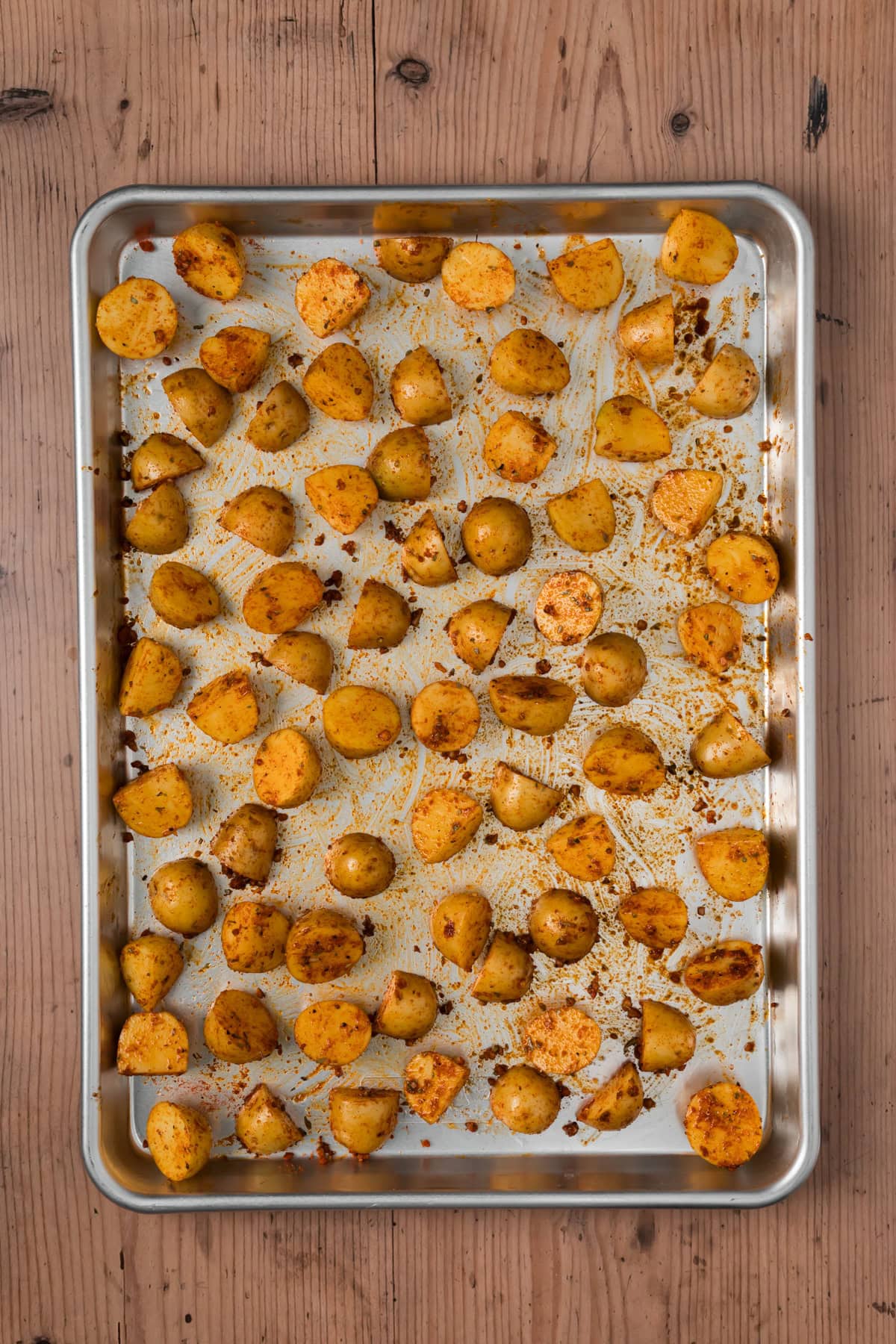 Potatoes coated in spices on a baking sheet.
