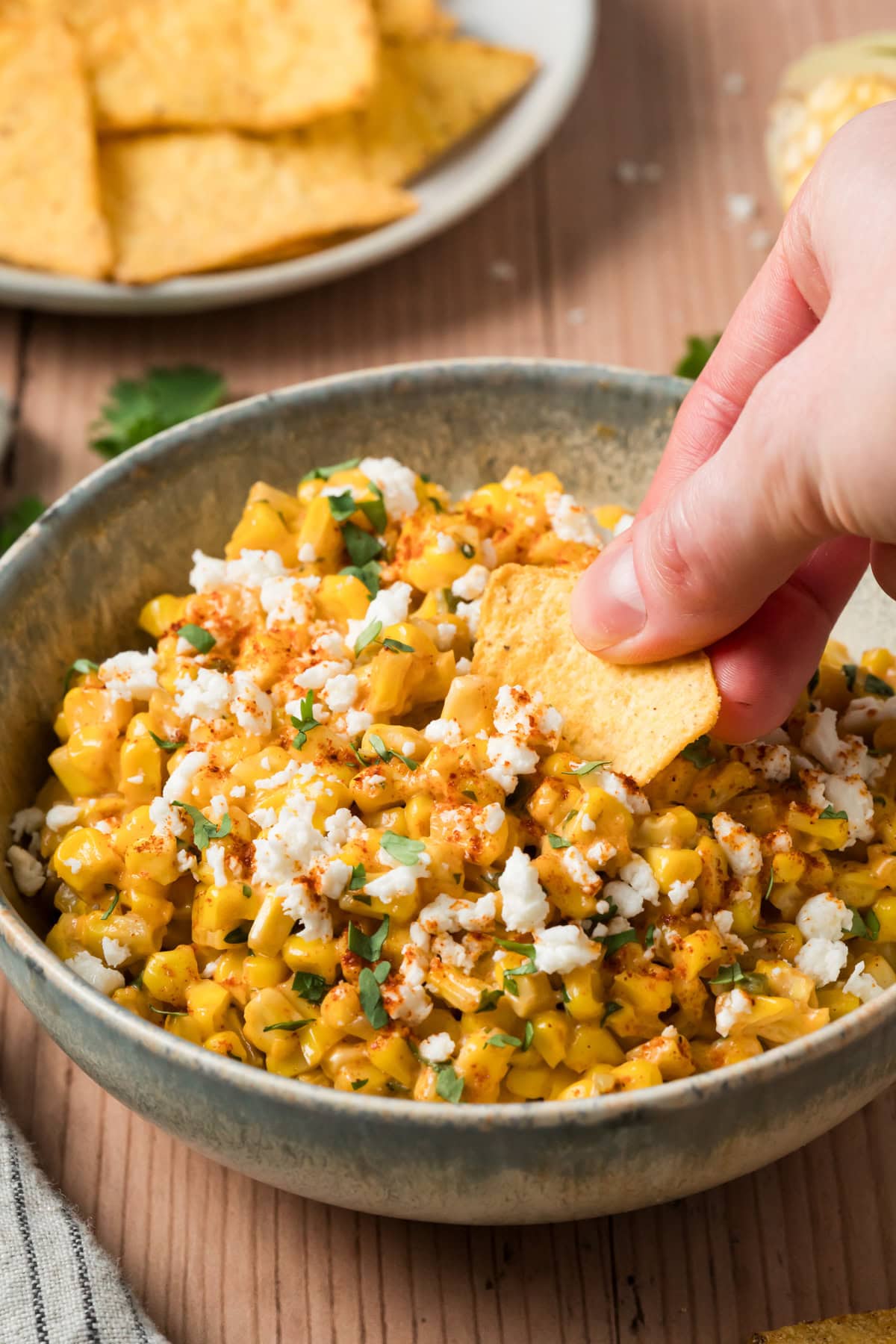 Tortilla chip scooping up elote dip.