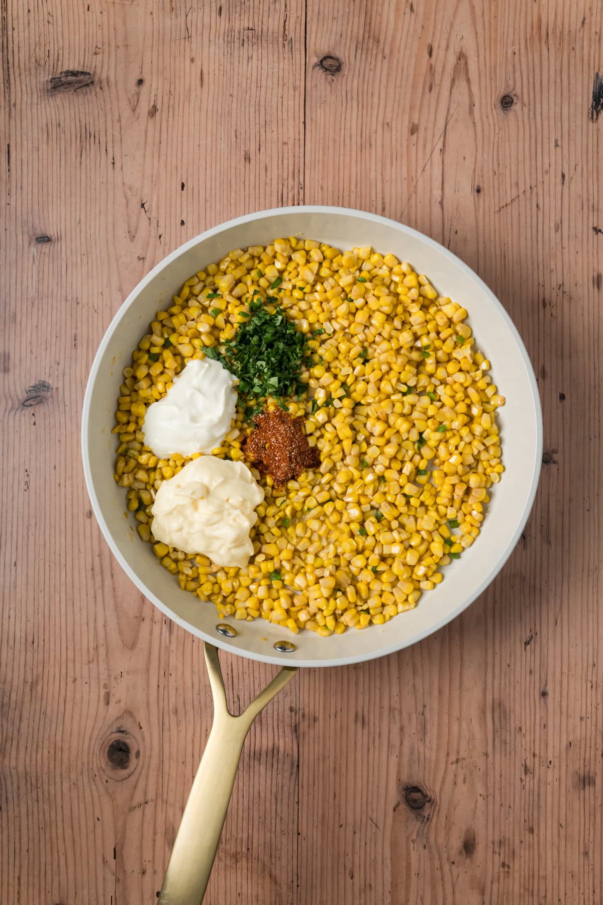 Mayo, sour cream, cilantro, and elote seasoning added to the pan.