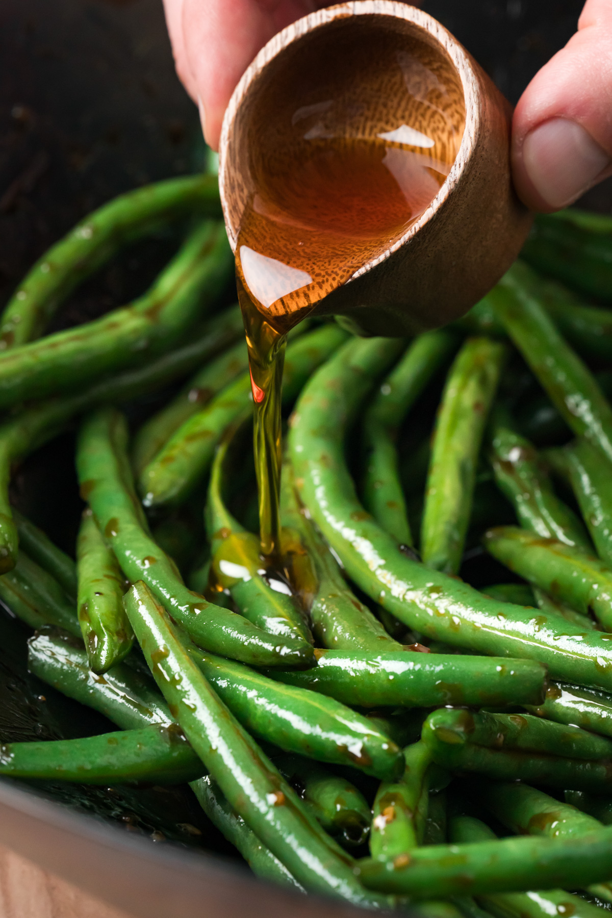 Sesame oil being poured over Chinese green beans.