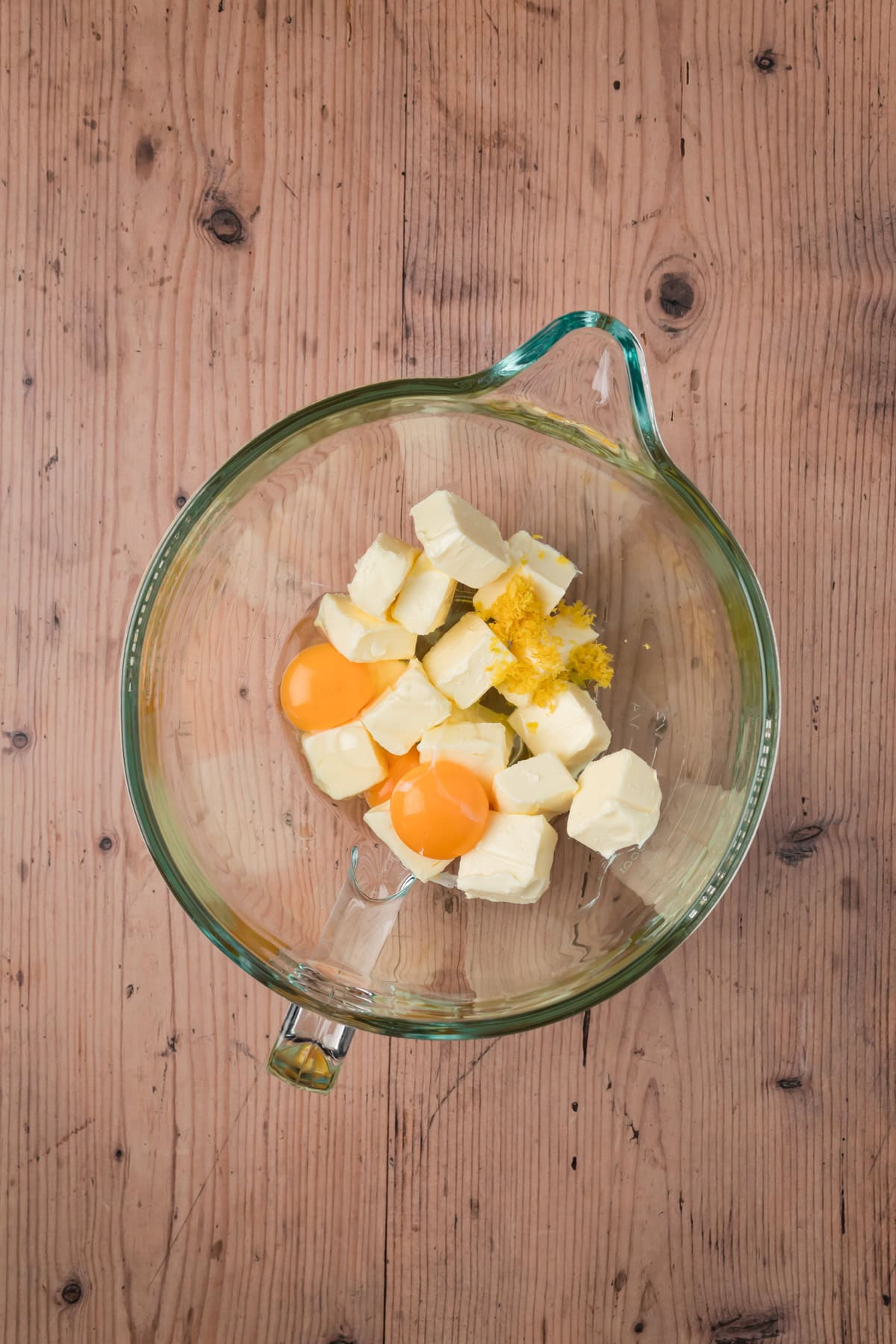 Butter, eggs, and lemon zest in a glass bowl.
