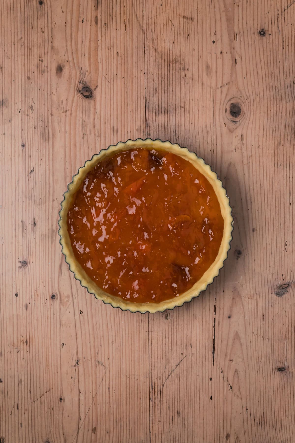 Apricot preserves spread out in the tart pan.
