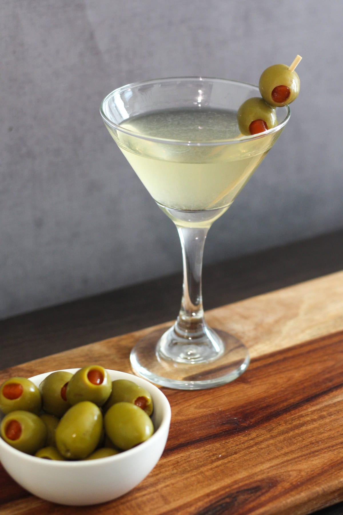 Dirty martini with a small bowl of olives on the side.