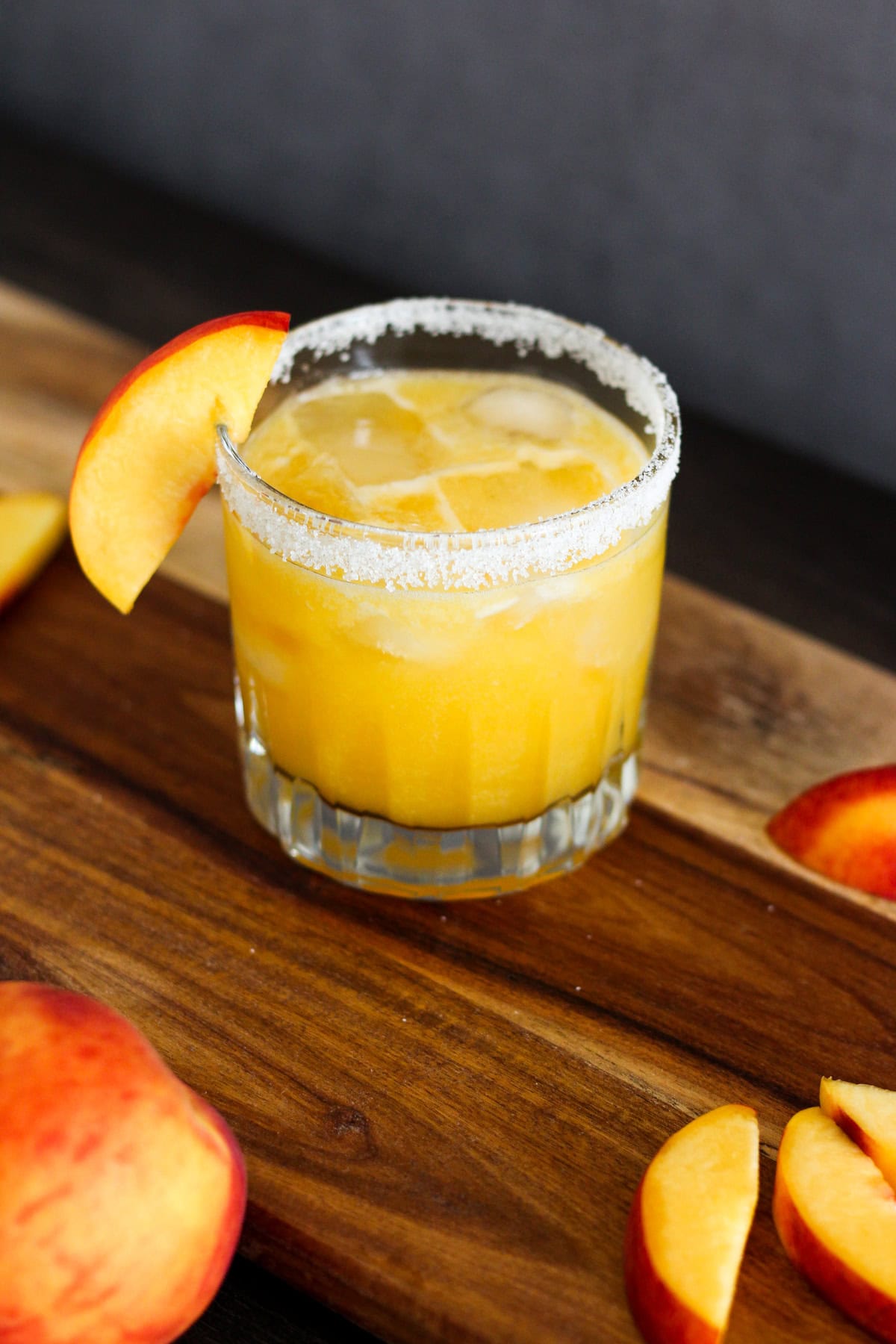 Peach margarita with a slice of peach on the rim.