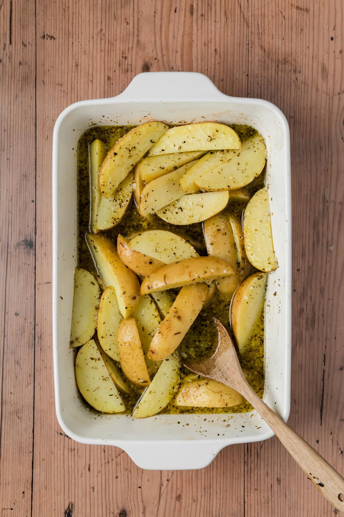 Potatoes added to the baking dish and coated in the liquid.