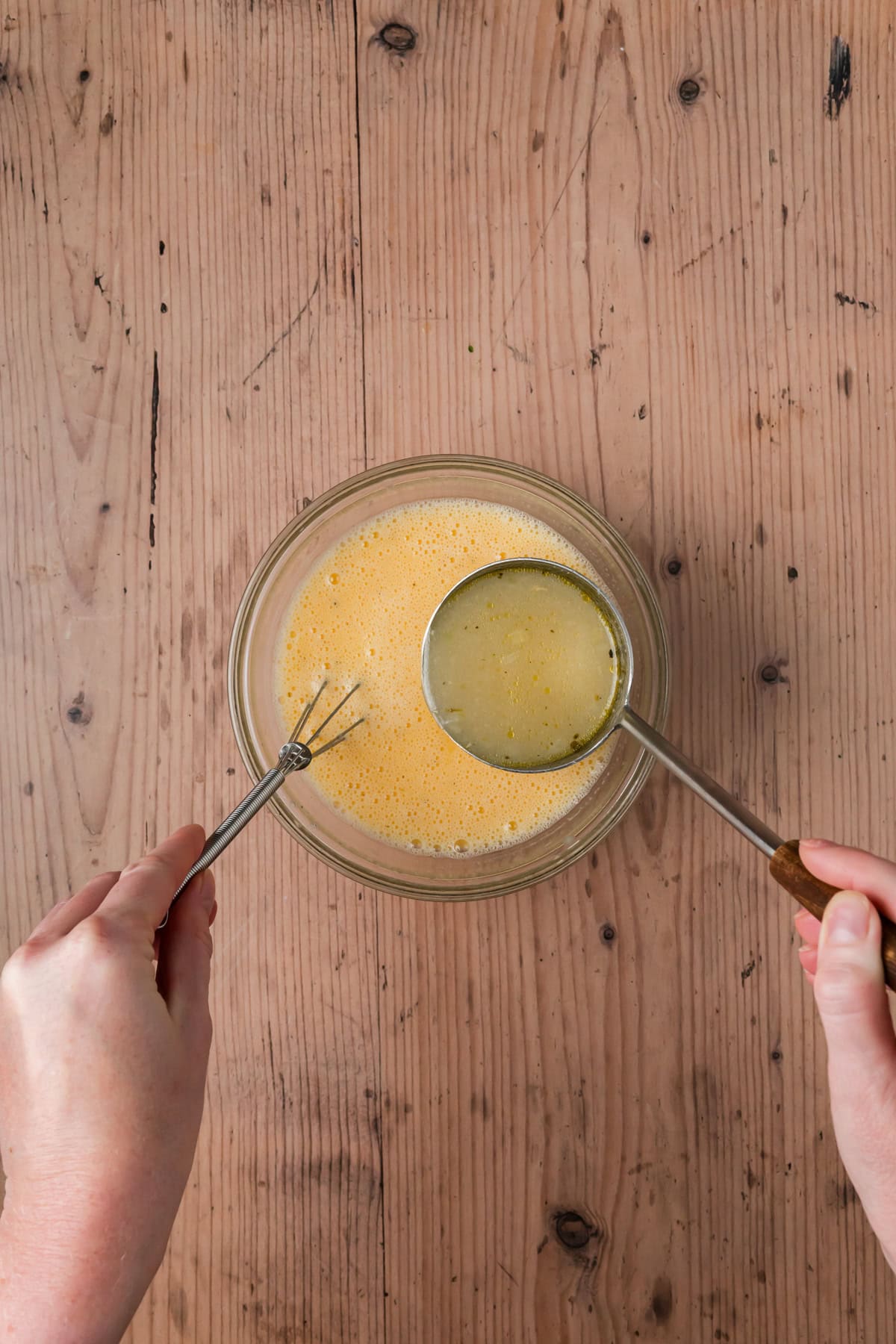 Soup being ladled into the egg mixture.