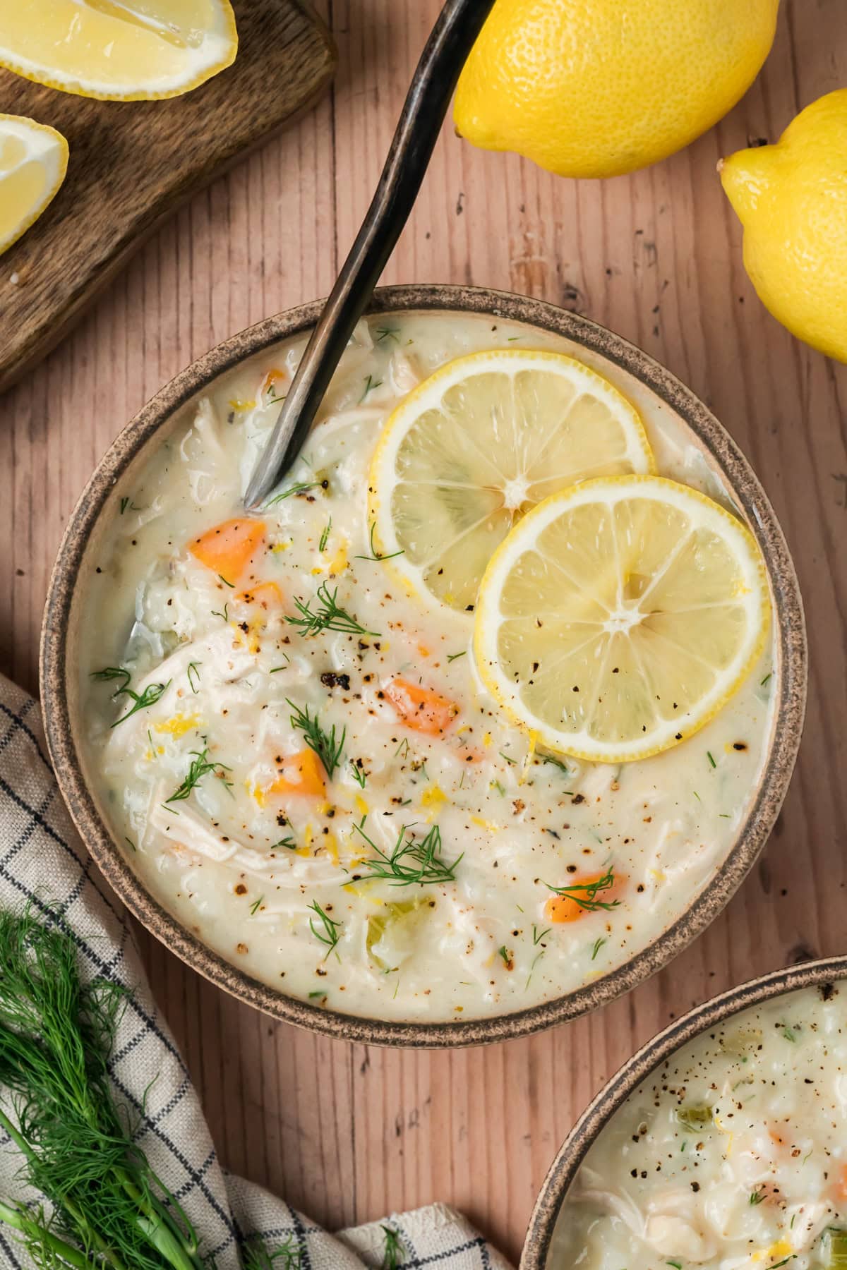 Avgolemono Soup in a bowl with fresh pepper and lemon slices.