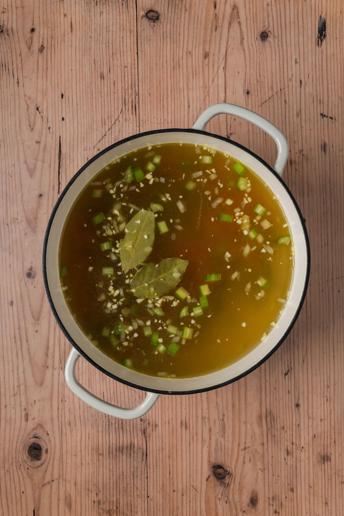 Chicken stock and bay leaves added to the Dutch oven.