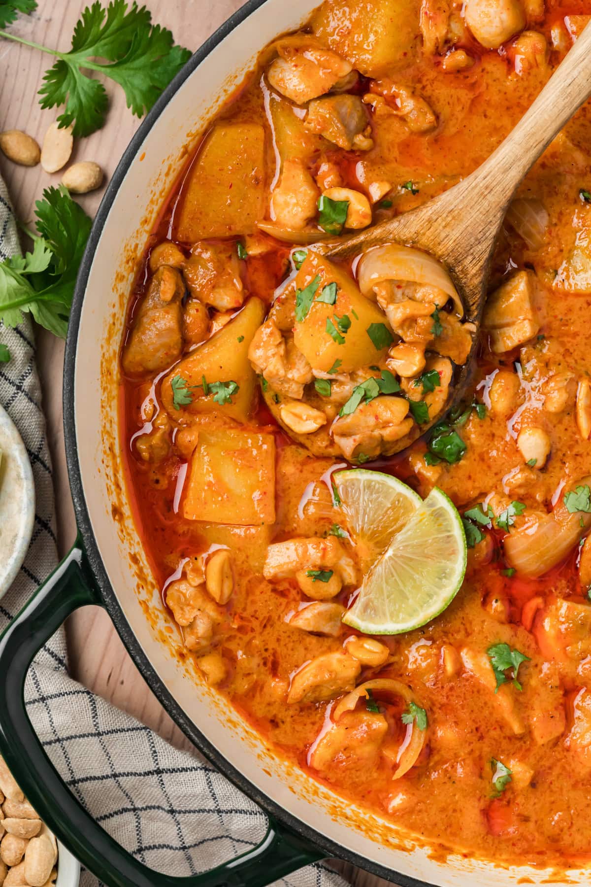 Wooden spoon of curry coming out of the pot.