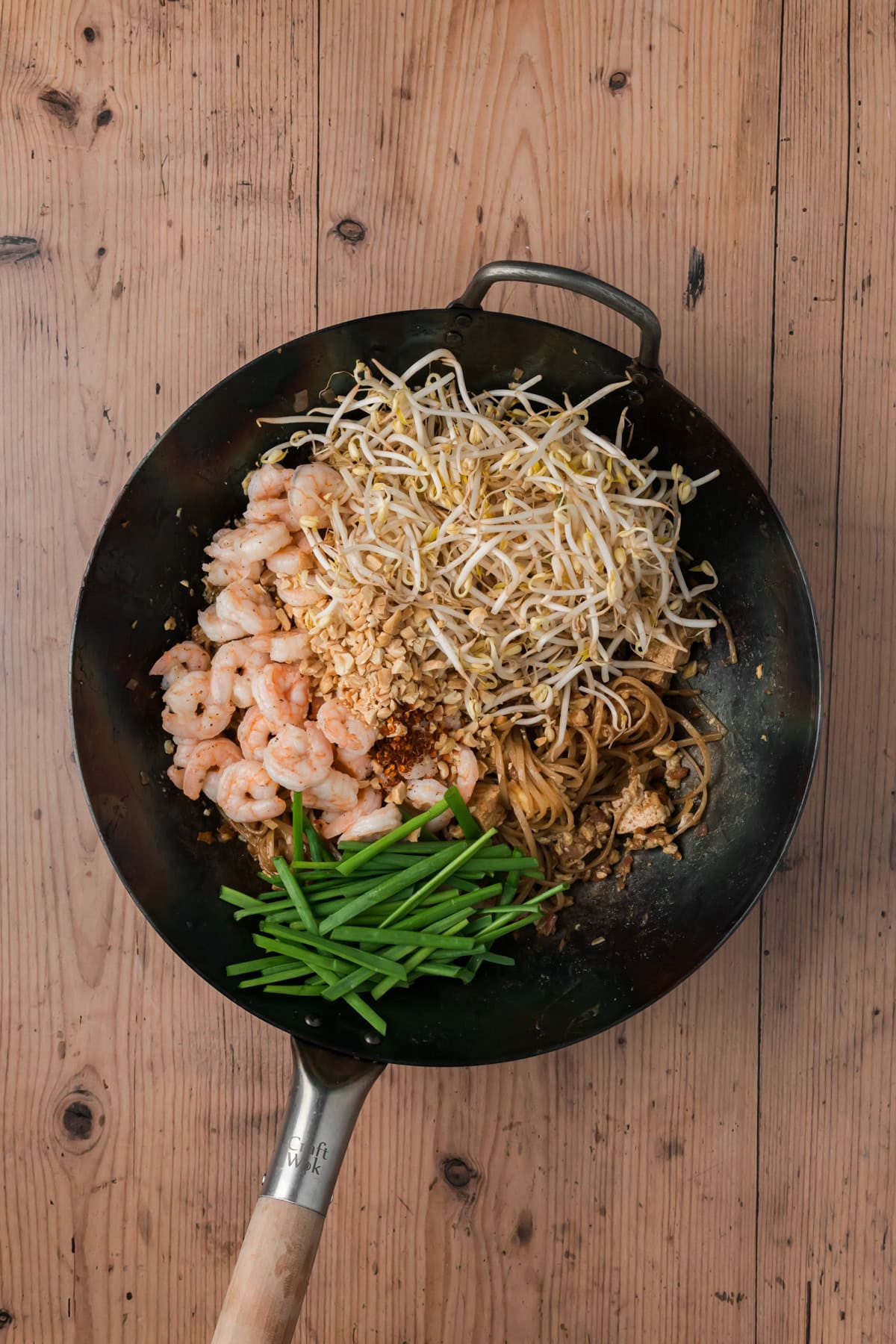Shrimp, bean sprouts, chili flakes, garlic chives, and peanuts added to the wok.