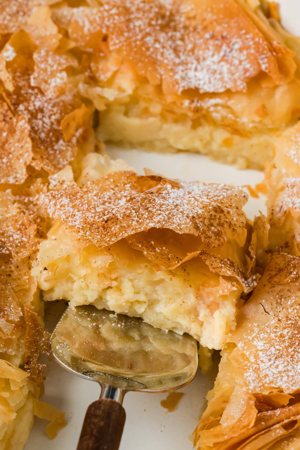 A slice of bougatsa being lifted out of the dish.