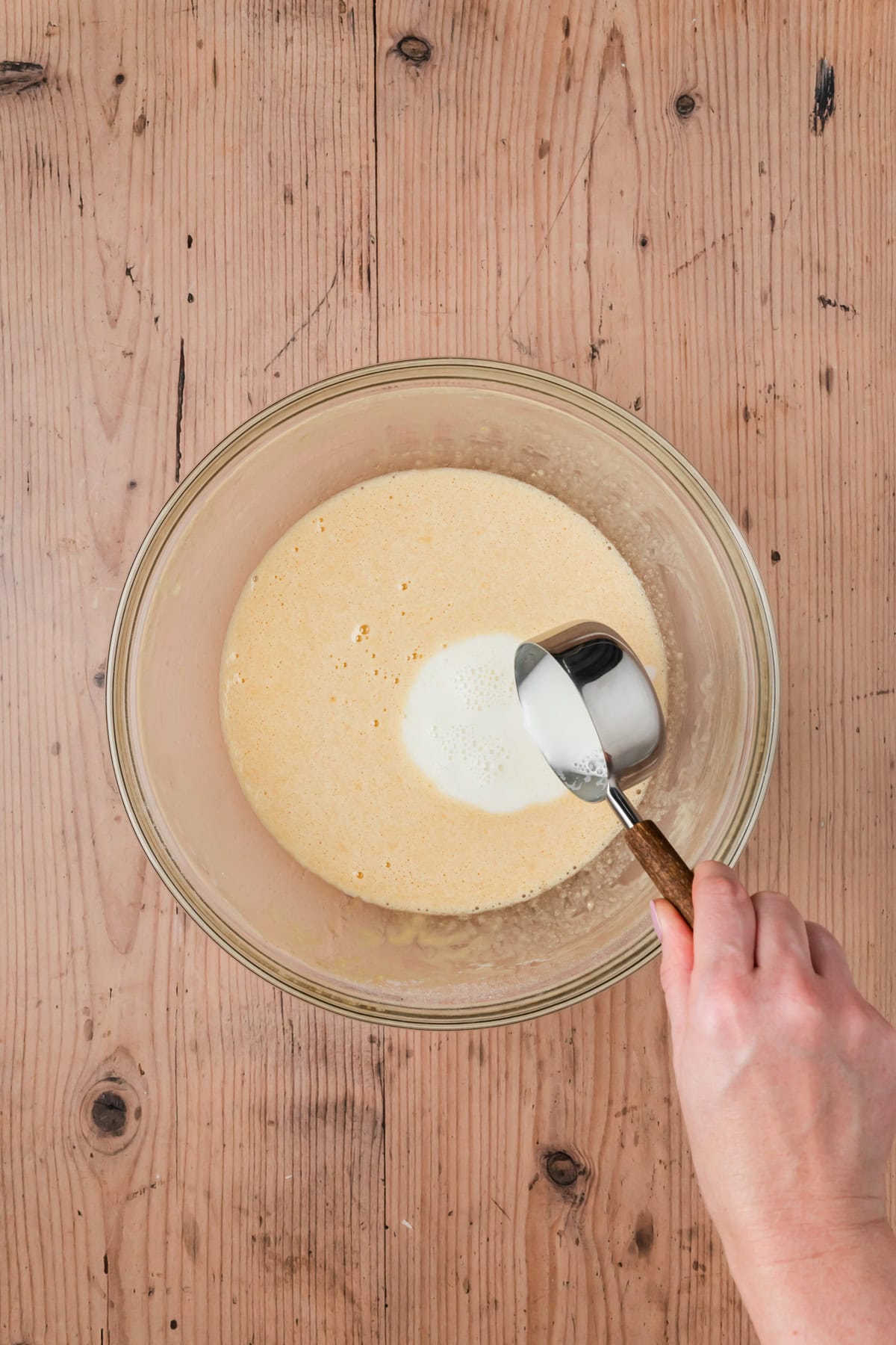 Milk being added to the egg mixture to temper.