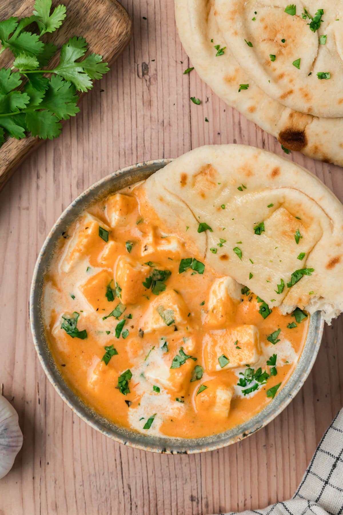 Paneer butter masala with naan bread on the side. 