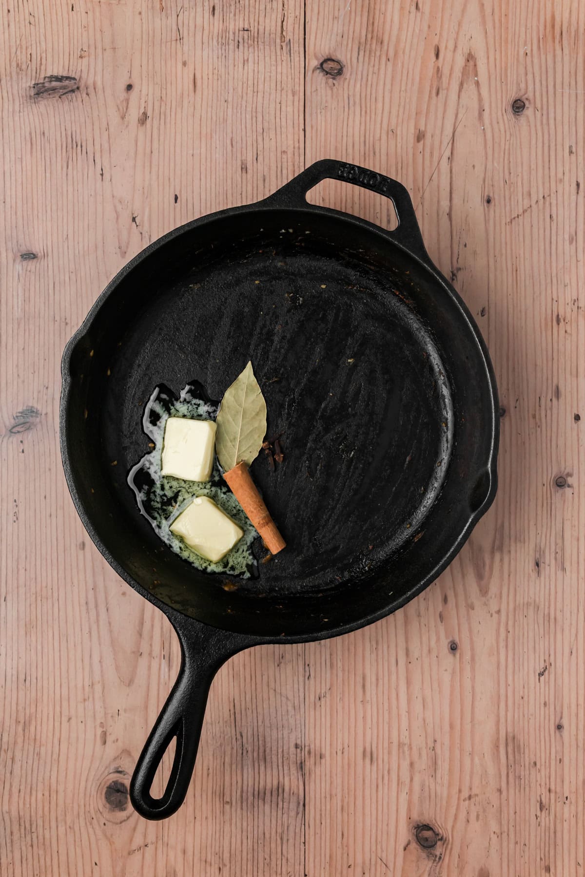 Butter, bay leaf, cinnamon stick, and cloves added to the skillet. 